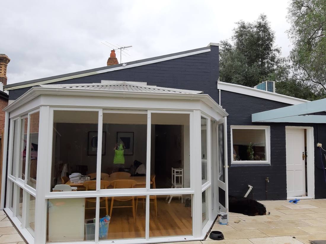 Peninsula-style home exterior with sunroom, repainted